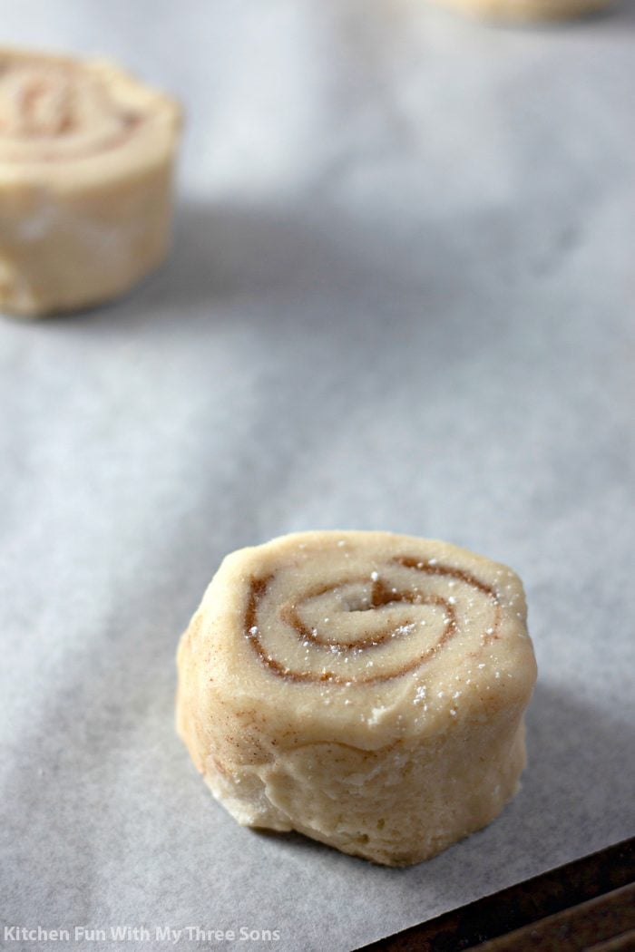 Slices of cinnamon roll cookie dough on parchment paper