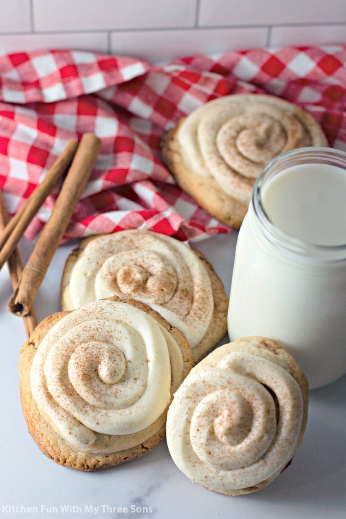 Frosted Cinnamon Roll Cookies with a red checkered napkin and a glass of milk