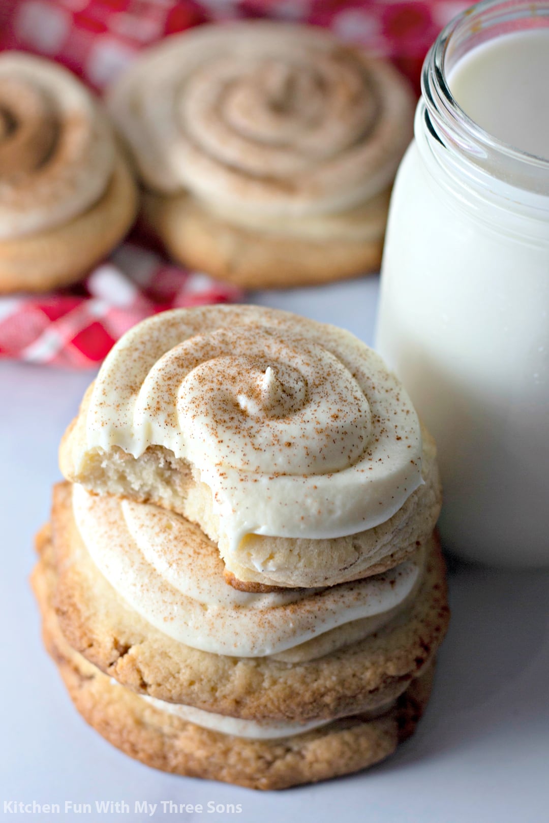 stacked Frosted Cinnamon Roll Cookies next to a glass of milk