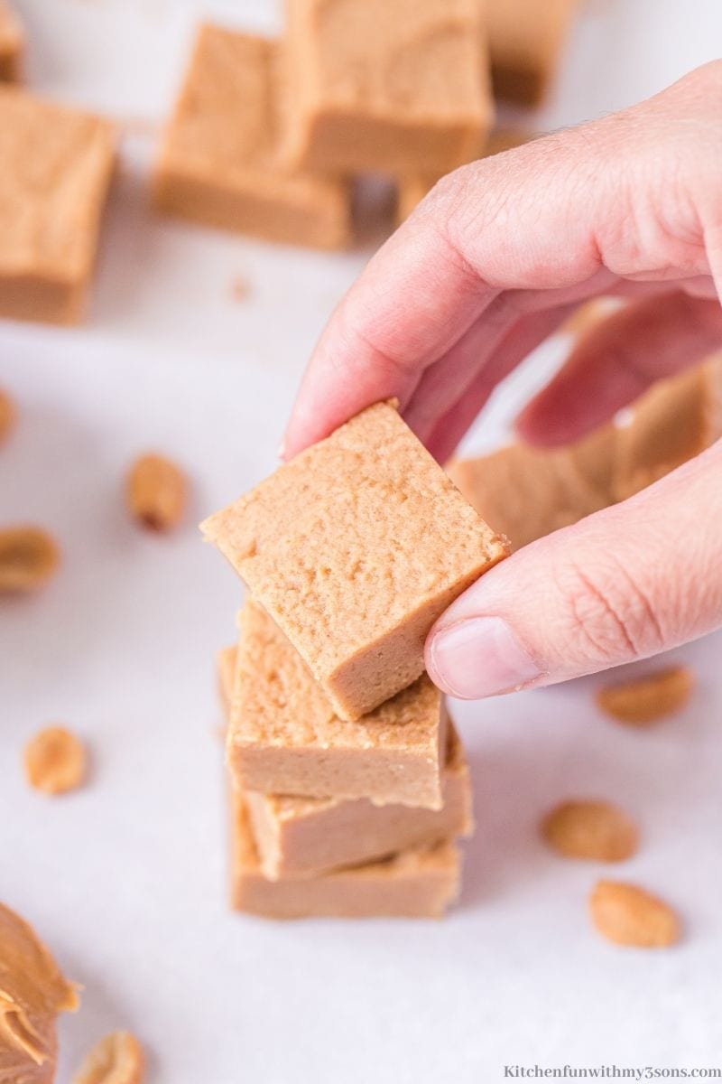 A hand holding a piece of the Easy Peanut Butter Fudge.