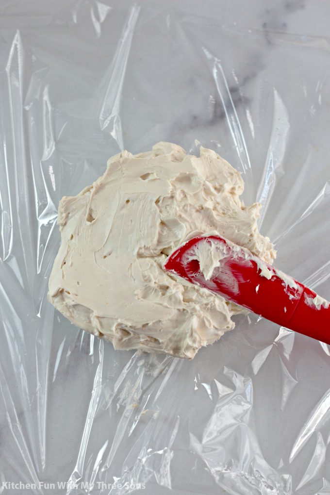spreading cream cheese mixture onto a piece of plastic wrap