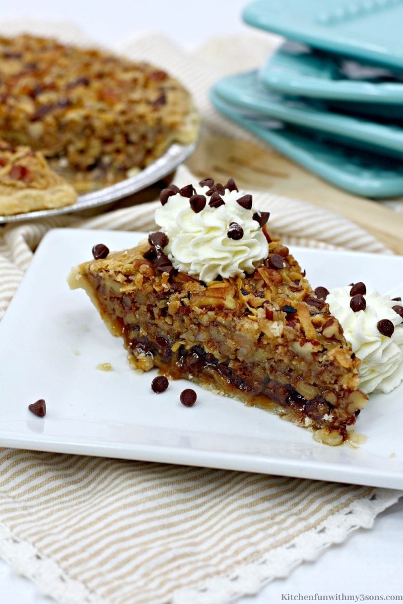 A slice of German Chocolate Pecan Pie with a dollop of whipped cream and chocolate chips sprinkled on top.