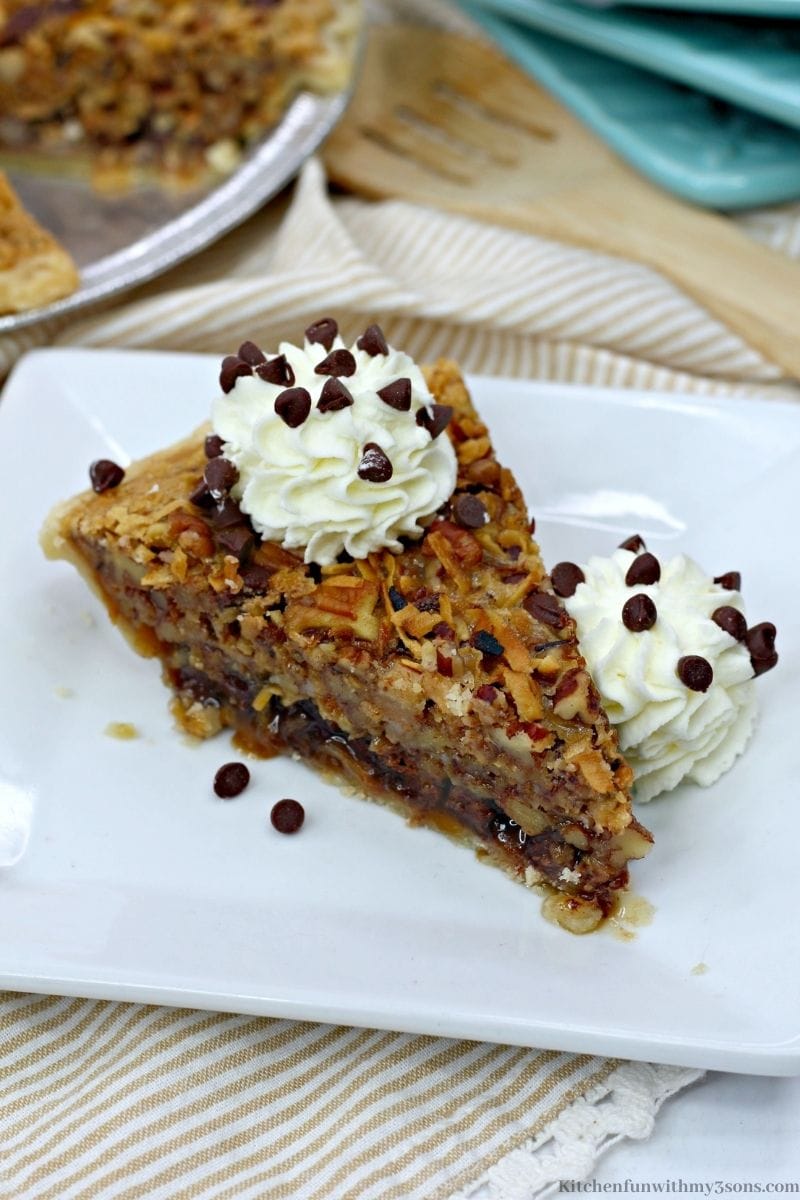 A plated pecan pie slice seen from above with whipped cream on top.