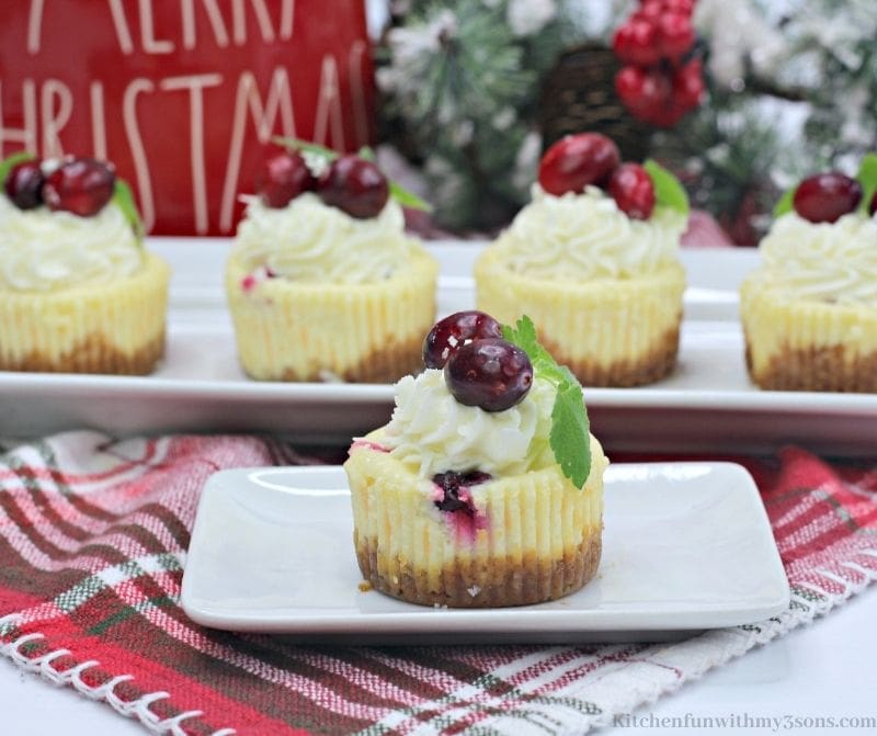 Mini White Chocolate Cranberry Cheesecake with Christmas decorations behind it.