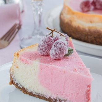 Pink Champagne Cheesecake with frosted grapes on a white plate