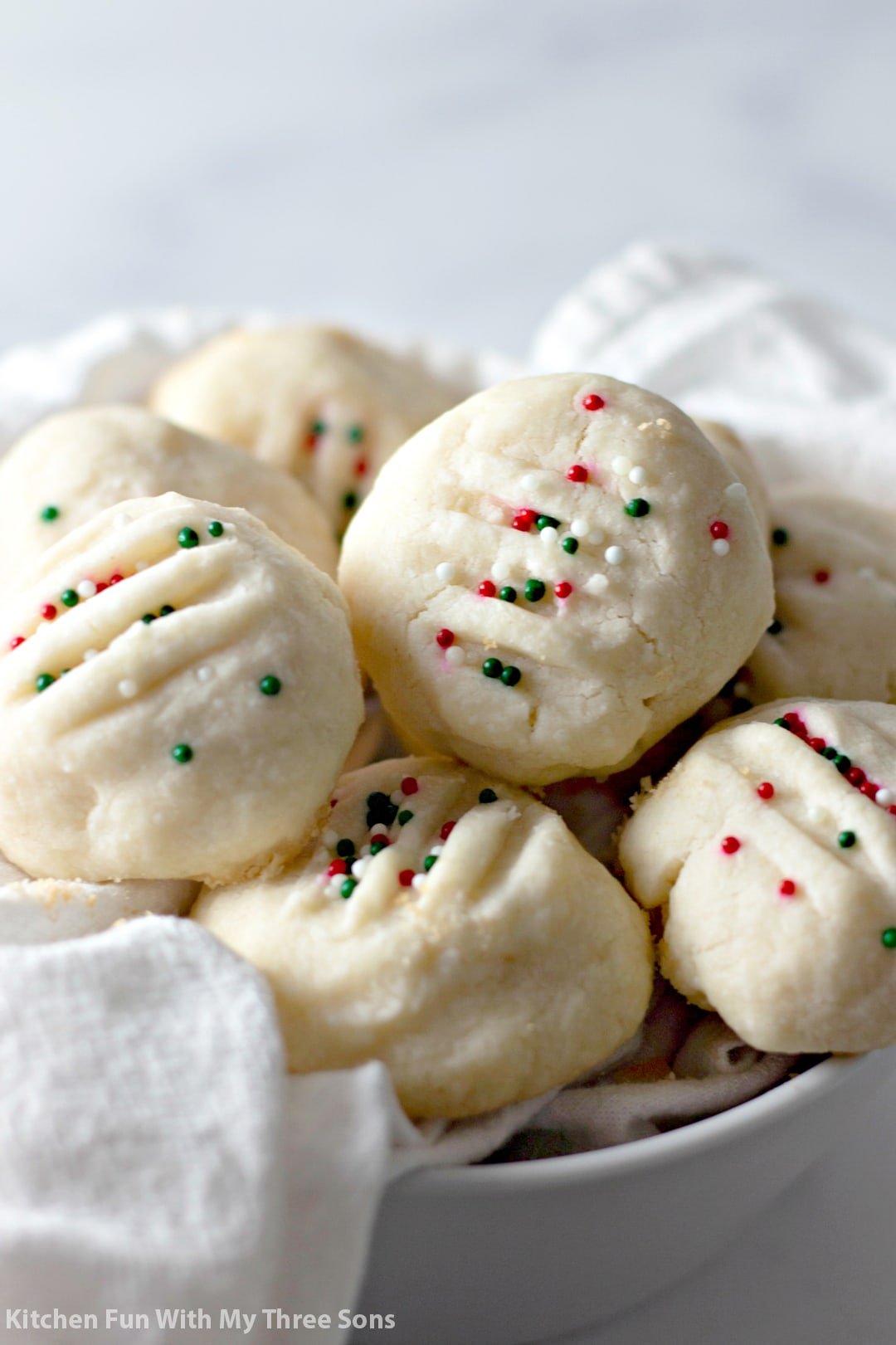 Whipped shortbread cookies piled in a cloth-lined dish.