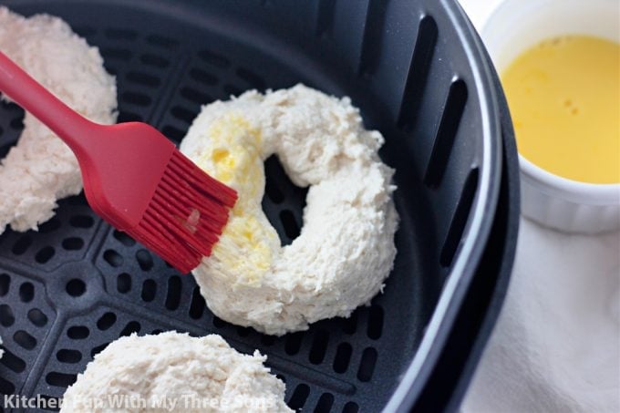 brushing egg wash over bagel dough