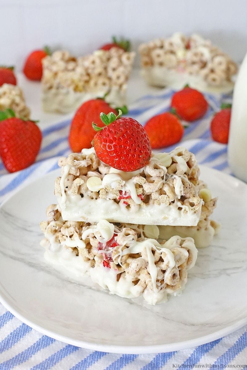 Two of the Berries and Cream Cereal Bars stacked on top of each other with a strawberry.