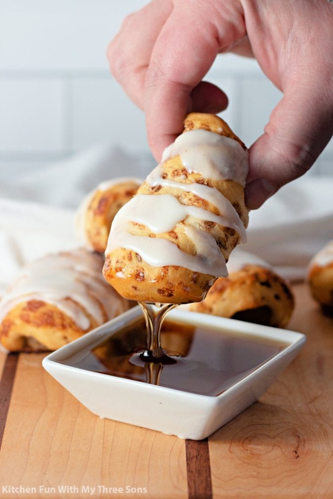 dipping the breakfast rolls in maple syrup
