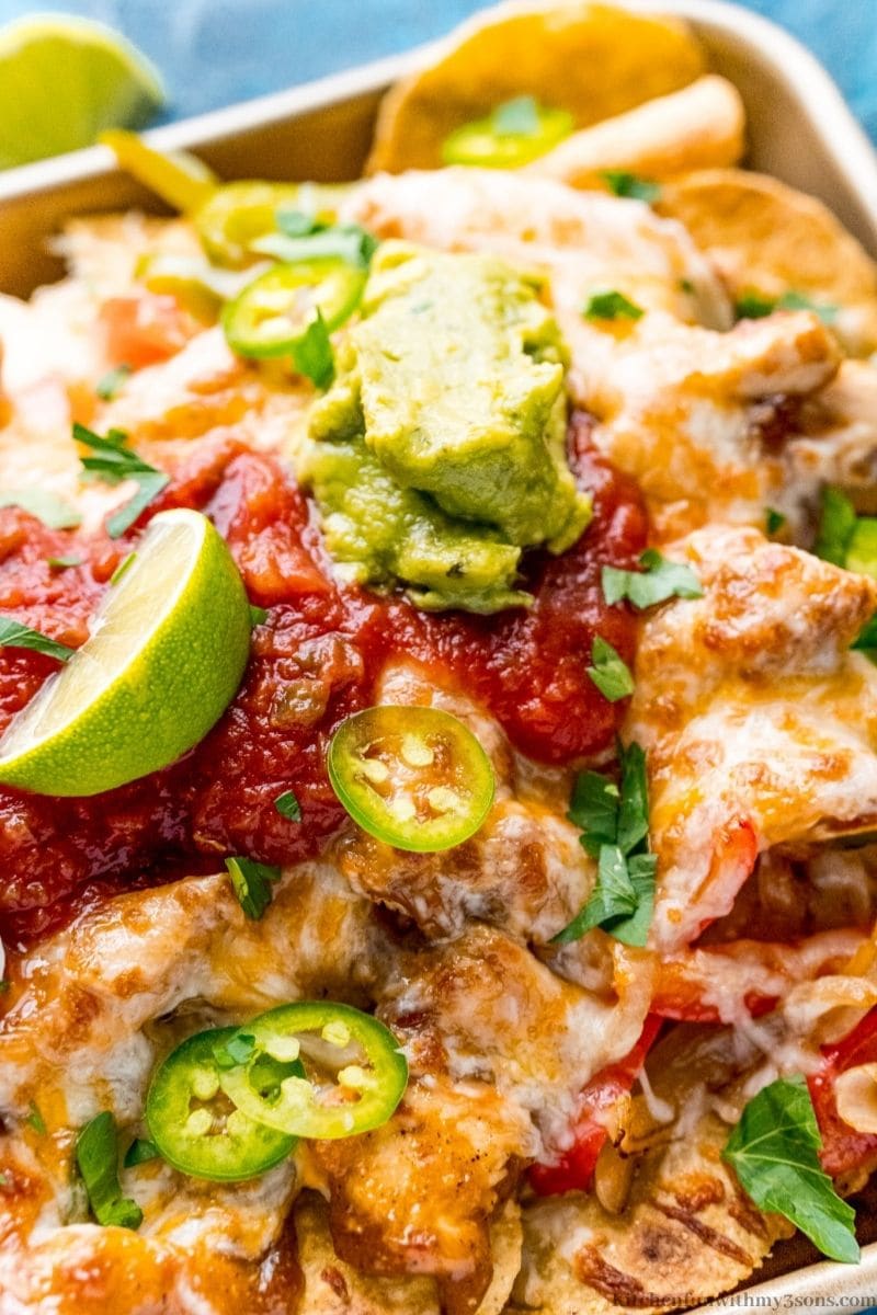 Nachos with lime wedges and guacamole.