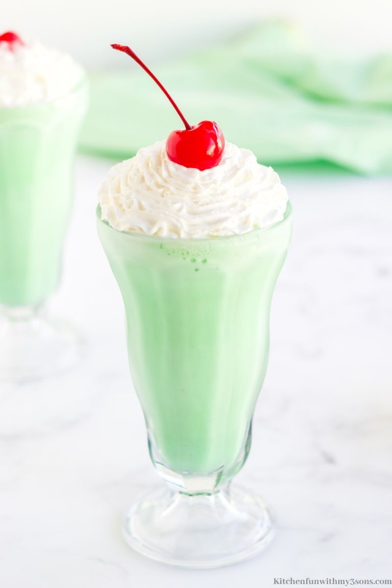 A homemade Shamrock Shake in a milkshake glass, topped with whipped cream and a cherry.