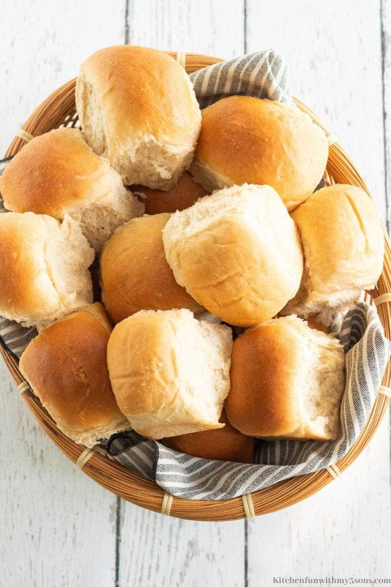 The rolls in a basket on top of a striped gray and white cloth.