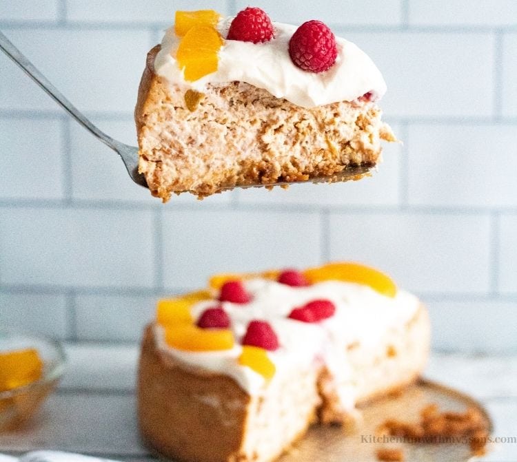 A spatula lifting up a slice of the Peach Swirl Cheesecake.