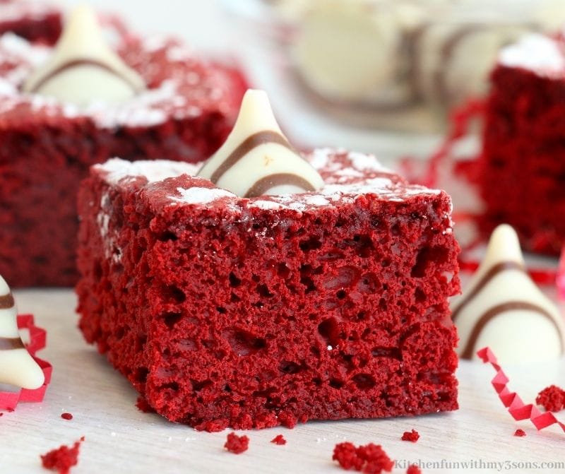 A piece of the red velvet cake with extra Hershey kisses around it.