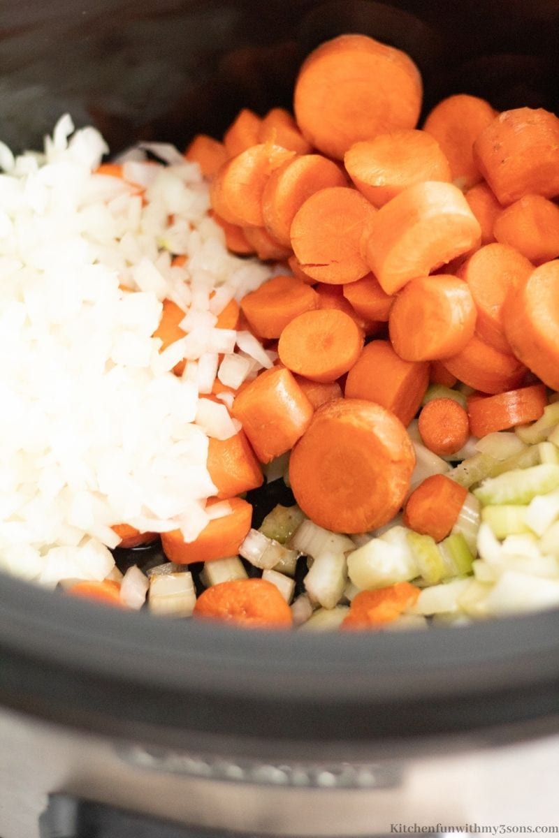 Adding the veggies into the slow cooker.