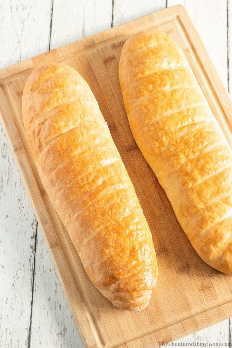 Two loaves of the French bread on a wooden cutting board.