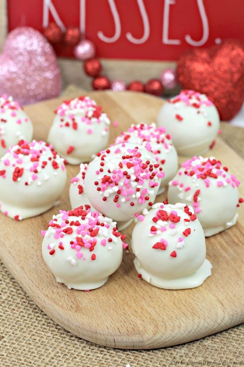 Valentine's Day Red Velvet Cake Balls with some valentines day decorations behind it.