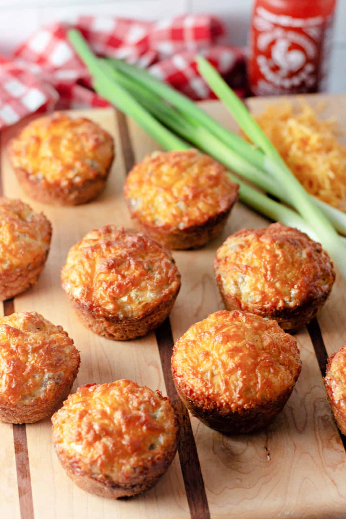 These easy Sausage Breakfast Muffins are packed with savory sausage, fluffy eggs, melted cheddar cheese, and Bisquick for the ultimate grab-and-go breakfast. top view of baked sausage breakfast muffins on a cutting board.