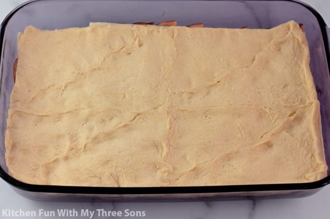 pressing crescent roll dough on top of the sandwich casserole. 