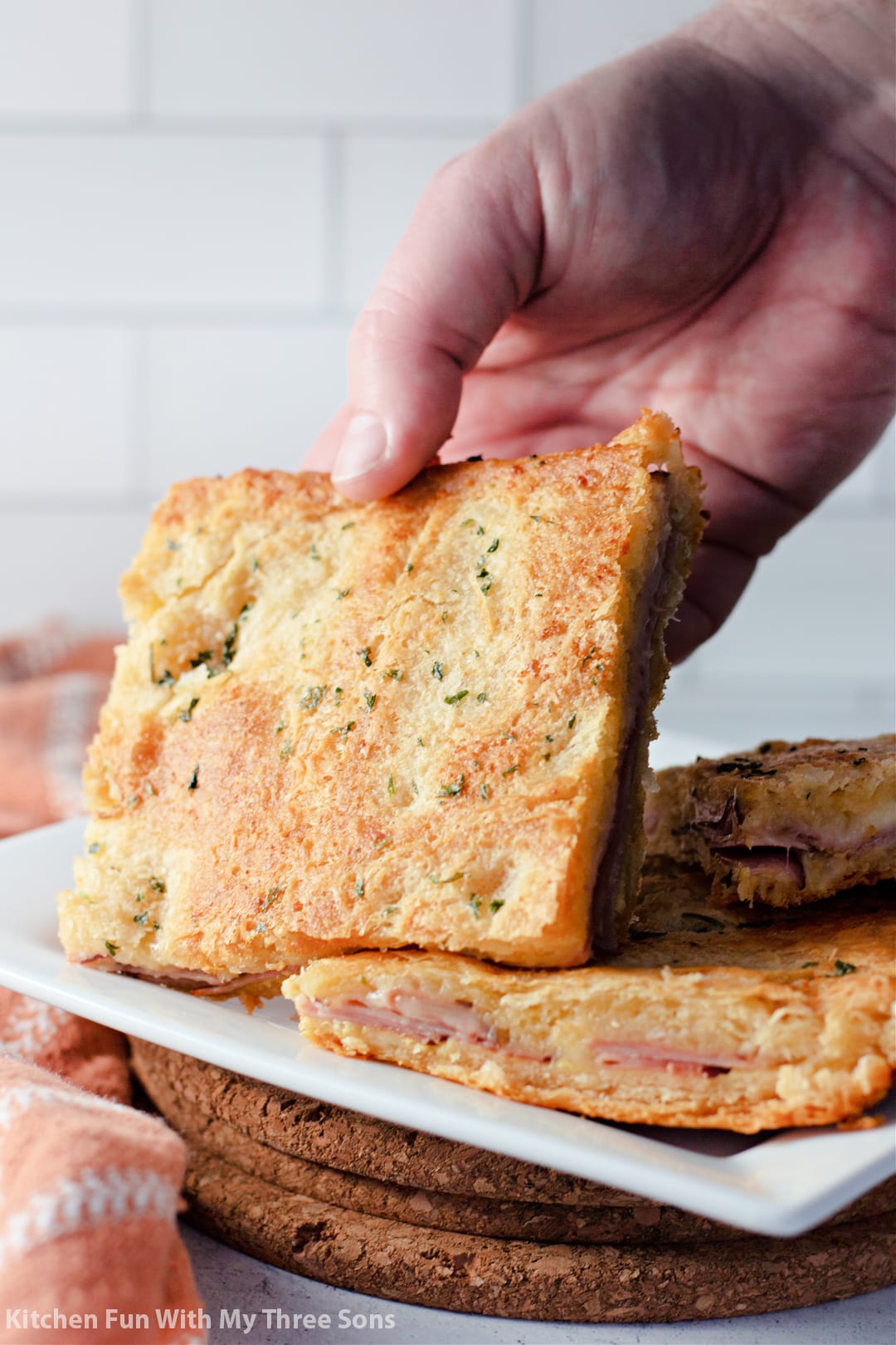 picking up a slice of Baked Ham and Cheese Sandwiches.