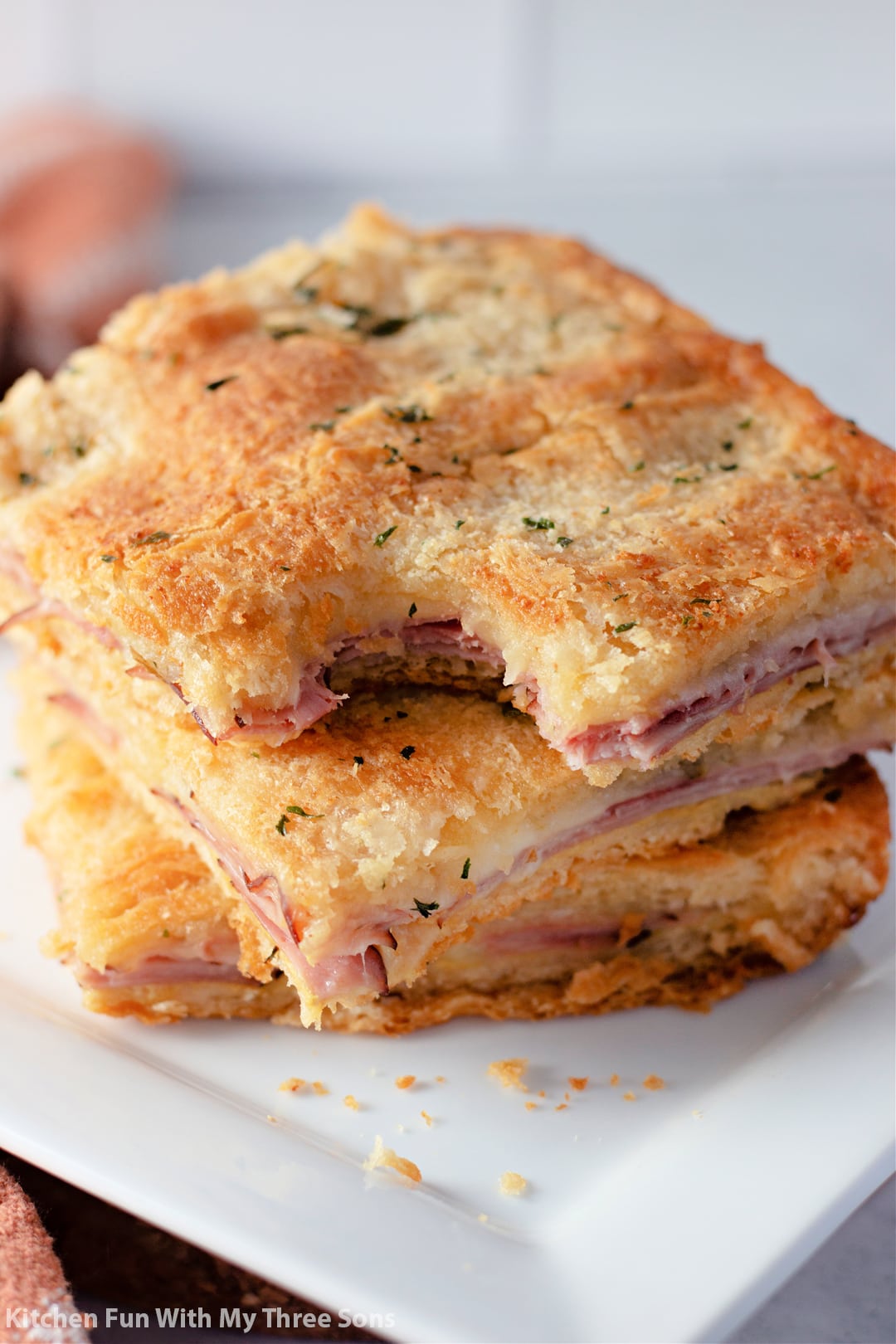 stacked Baked Ham and Cheese Sandwiches with a bite taken out.