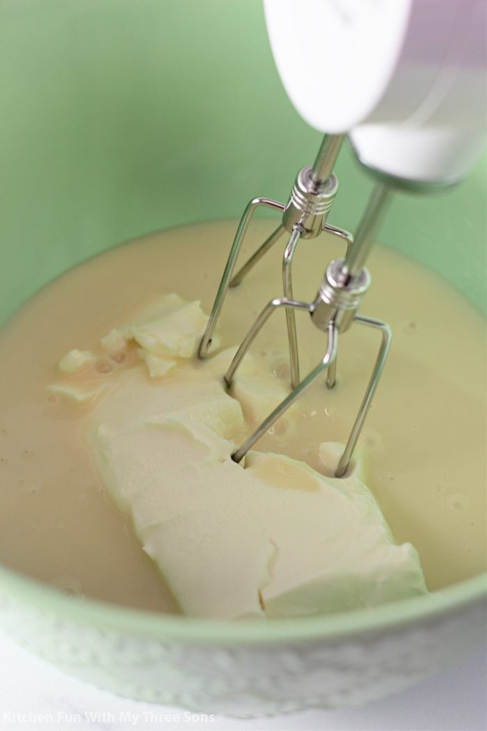 A mixer beating cream cheese and pudding