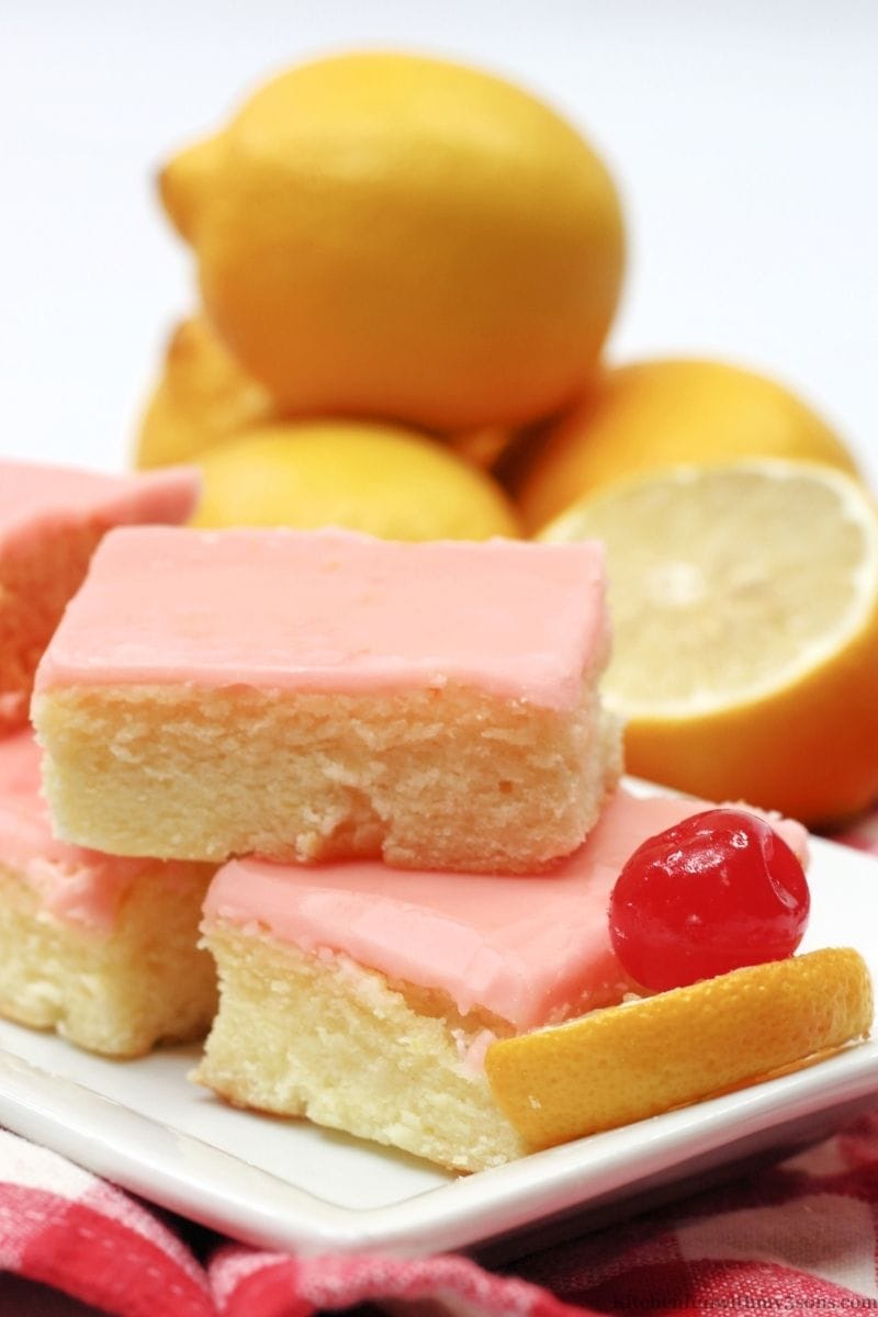 Cherry Lemonade Bars with a cherry and lemon wedge in front of them.