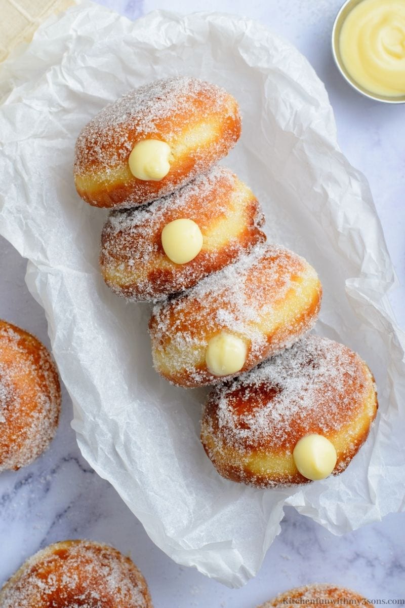 Cream Filled Brioche Donuts lined up in a dish with parchment paper.