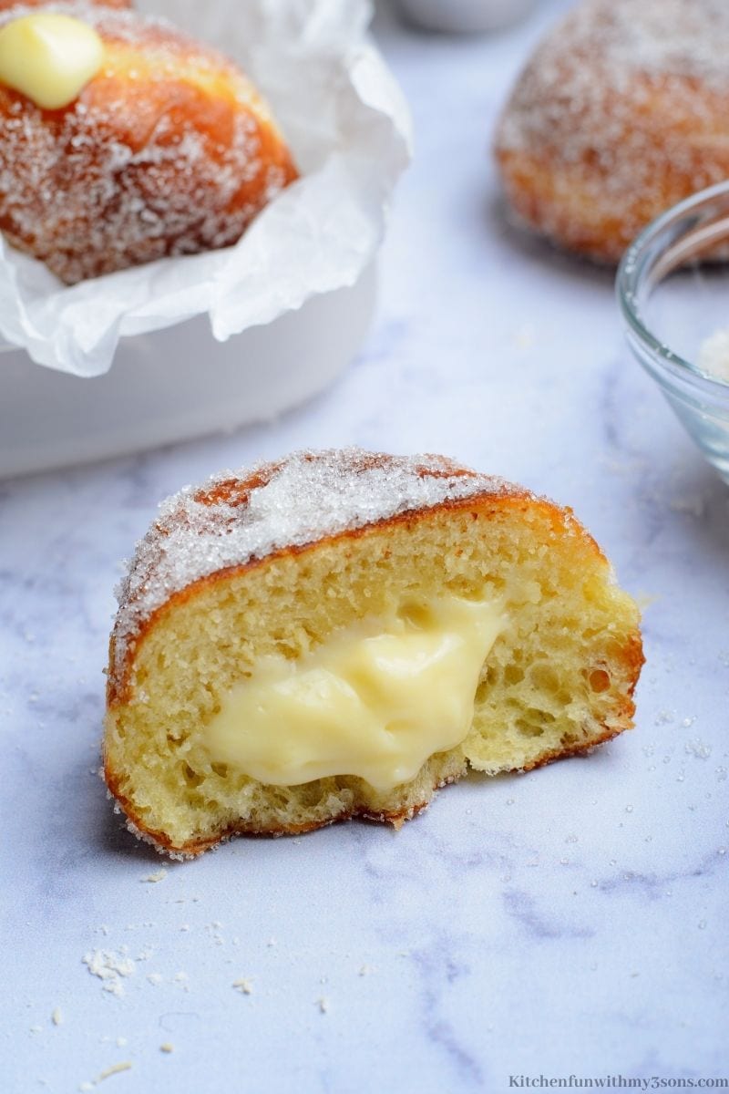 One of the Cream Filled Brioche Donuts cut in half with filling falling out.