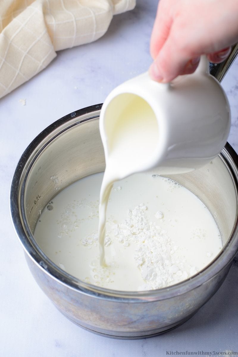 Pouring the milk into the saucepan with other ingredients.