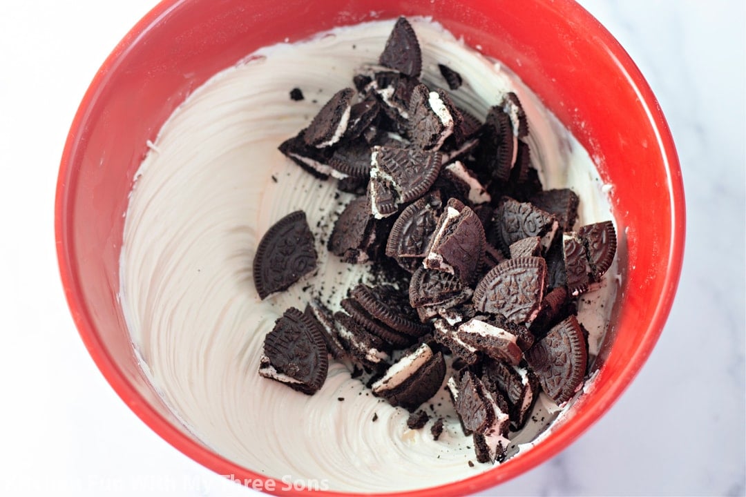 Chopped Oreo cookies added to a bowl with cream pie filling.