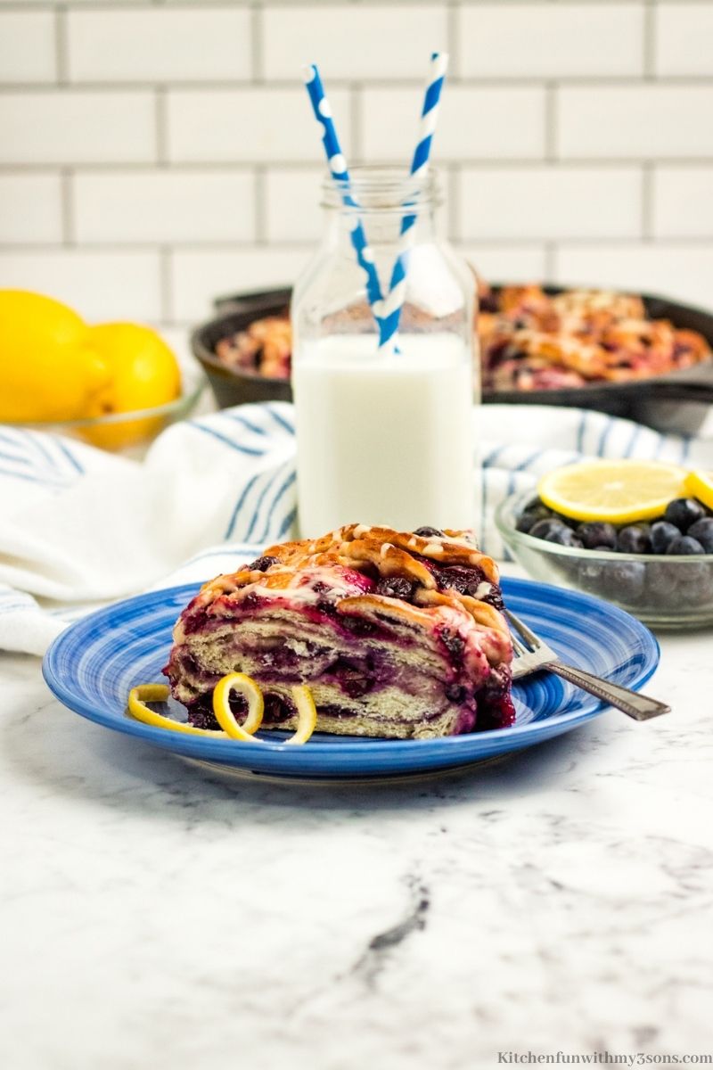 Lemon Blueberry Bread on a blue plate with milk behind it.
