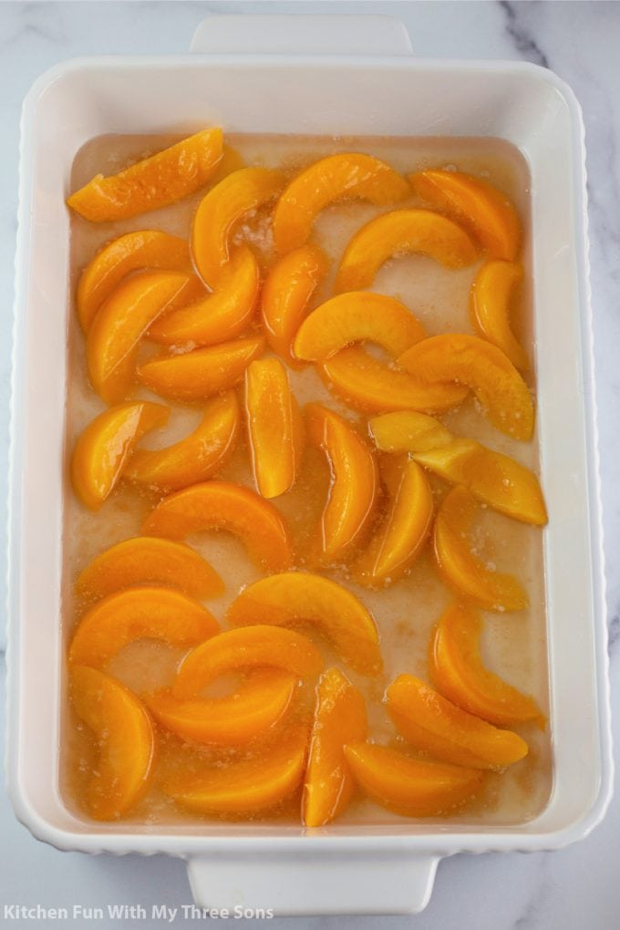 canned peaches in the bottom of the white baking dish.