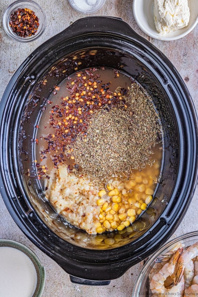 Adding the onion mixture, herbs, and kernels into the slow cooker.