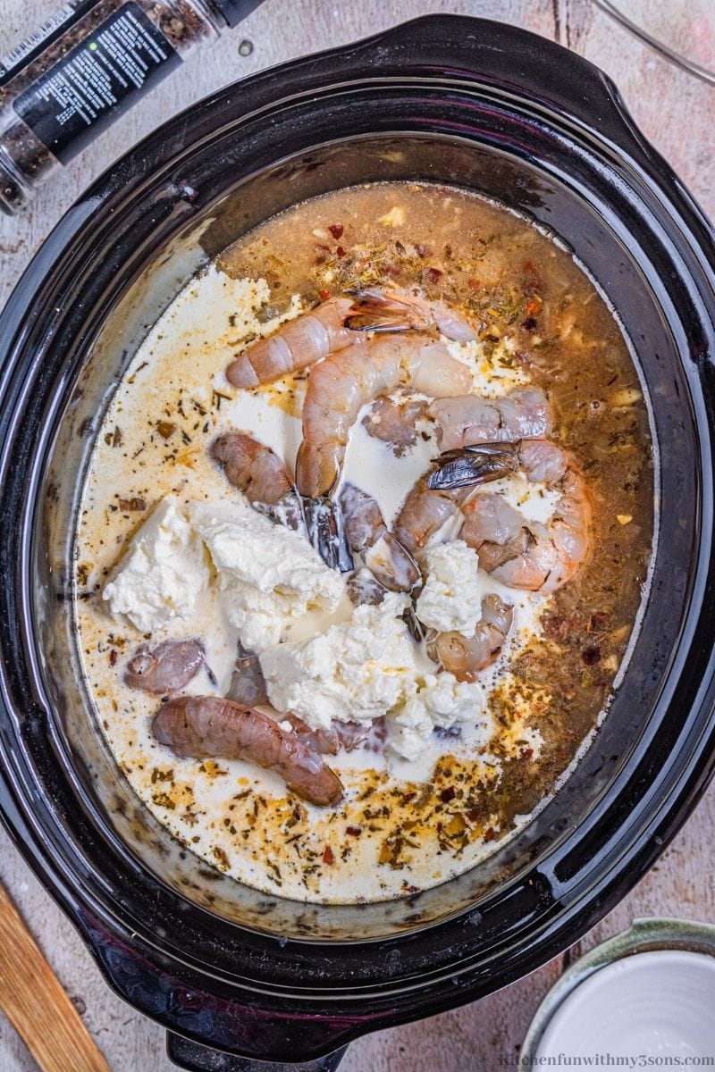 Adding the shrimp, cream cheese, and heavy cream into the slowcooker.