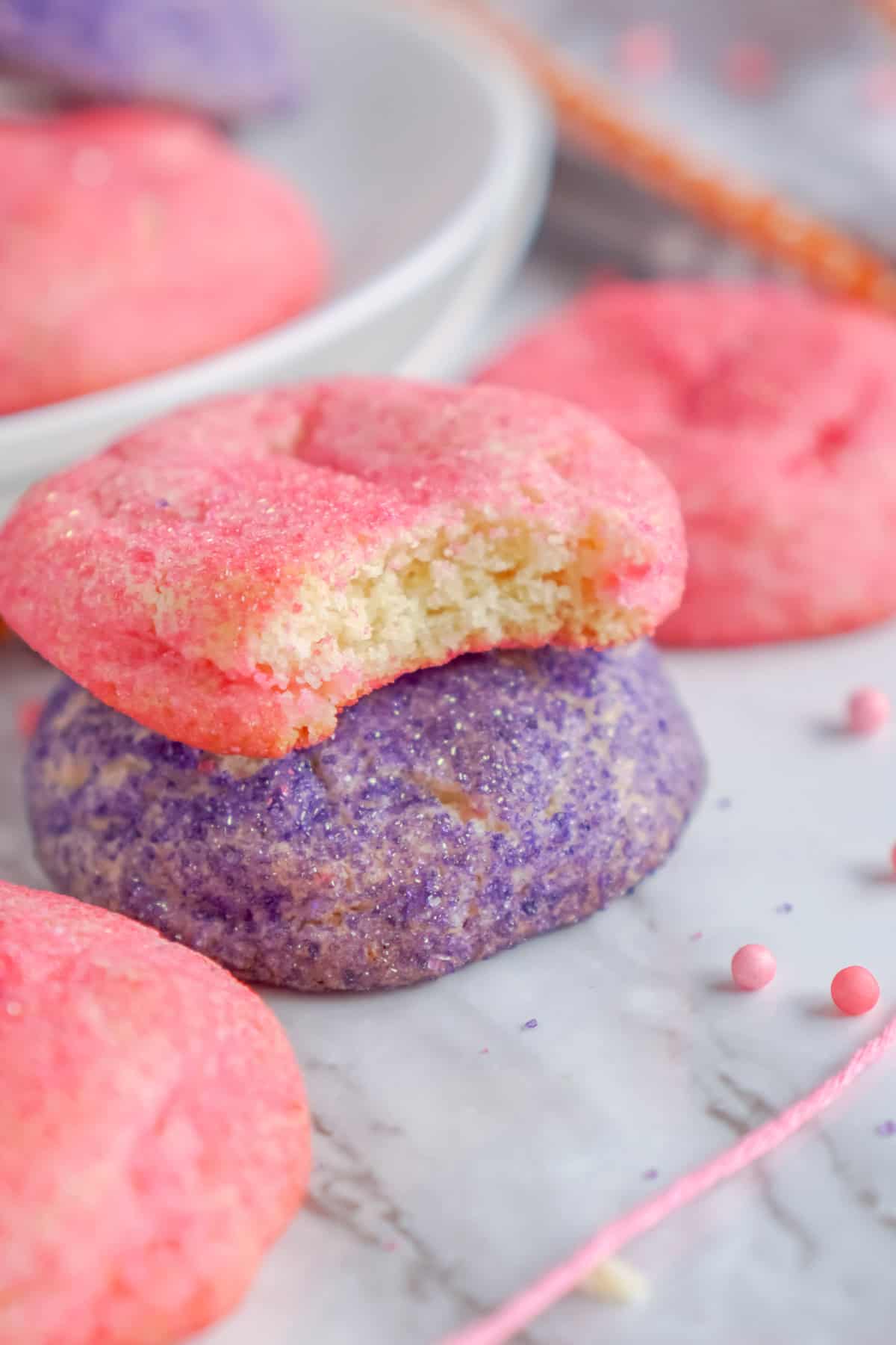 Pink and purple sugar cookies, one with a bite missing