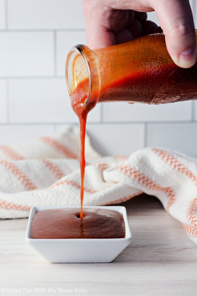 pouring homemade BBQ Sauce into a small dish.