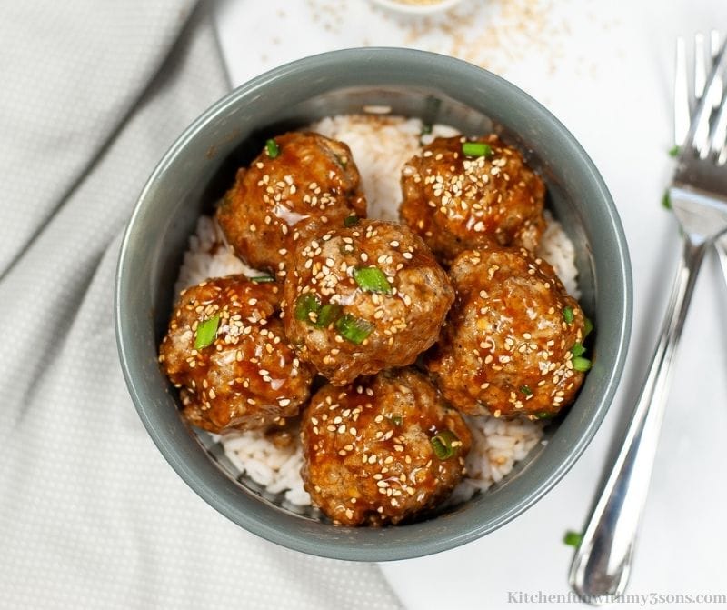 The Asian meatballs in a gray bowl over rice.