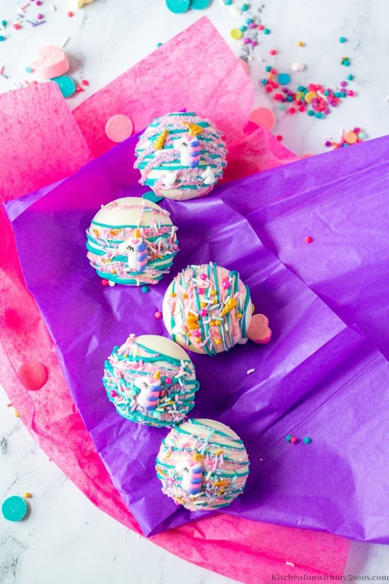 The Unicorn Hot Chocolate Bombs on purple and pink tissue paper.