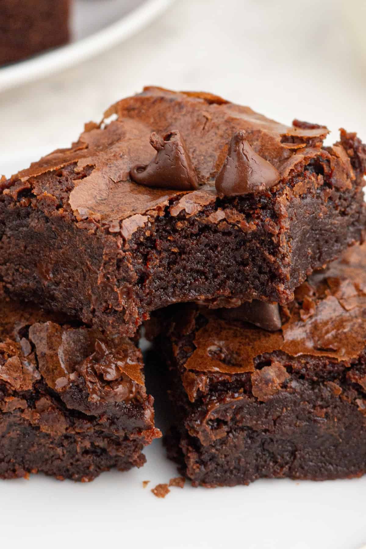 Resulting in decadently chewy, fudgy brownies with a perfectly crackly top, this is by far the Best Brownie Recipe I've ever tried. a bite taken out of a fudgy brownie