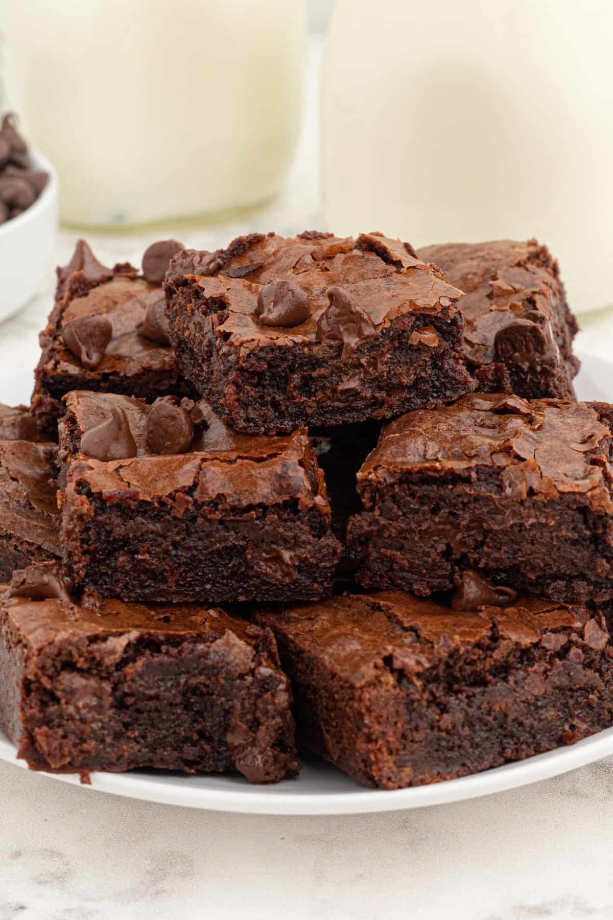 Resulting in decadently chewy, fudgy brownies with a perfectly crackly top, this is by far the Best Brownie Recipe I've ever tried. stacked fudgy brownies on a plate