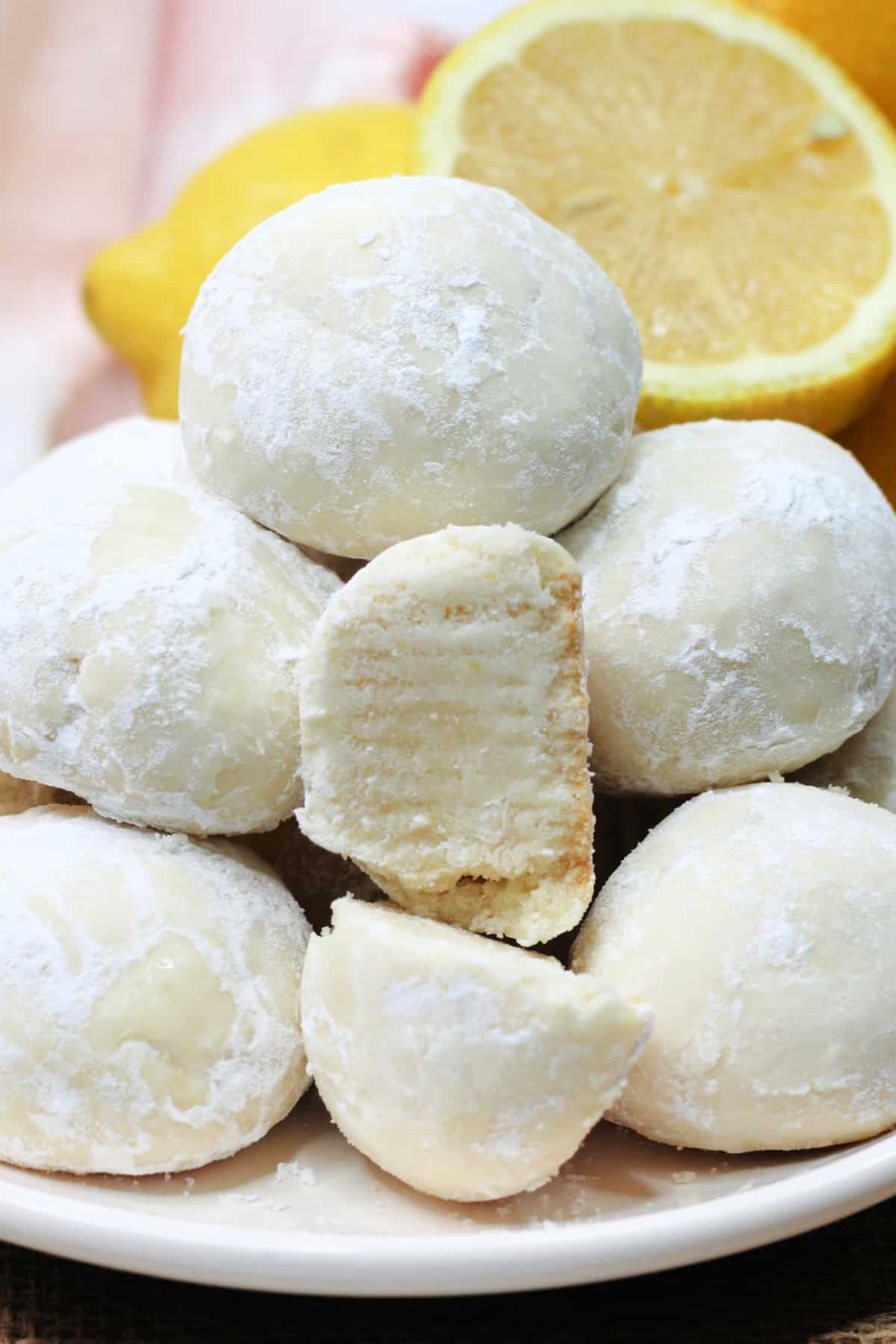 These Lemon Snowball Cookies are a refreshing melt-in-your-mouth twist on classic snowball cookies. close up of Lemon Snowball Cookies stacked on a plate