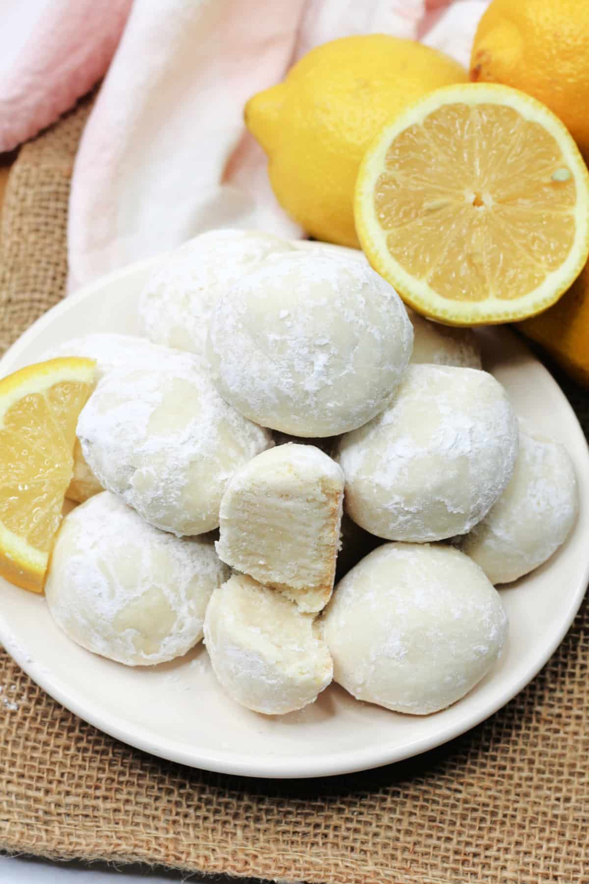 These Lemon Snowball Cookies are a refreshing melt-in-your-mouth twist on classic snowball cookies. top view of Lemon Snowball Cookies stacked on a plate