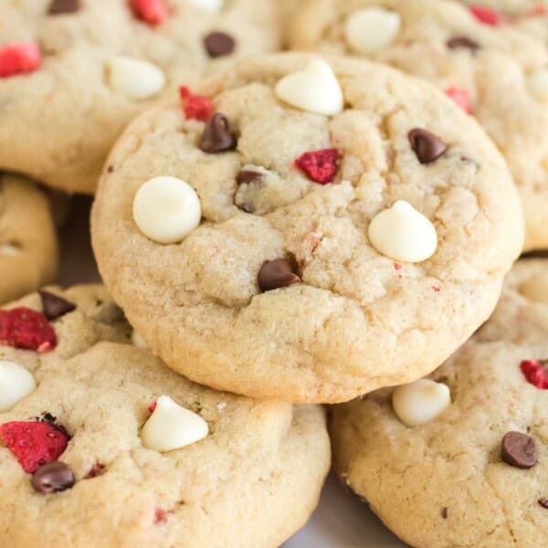 Close up of strawberry chocolate chip cookies stacked on a plate.
