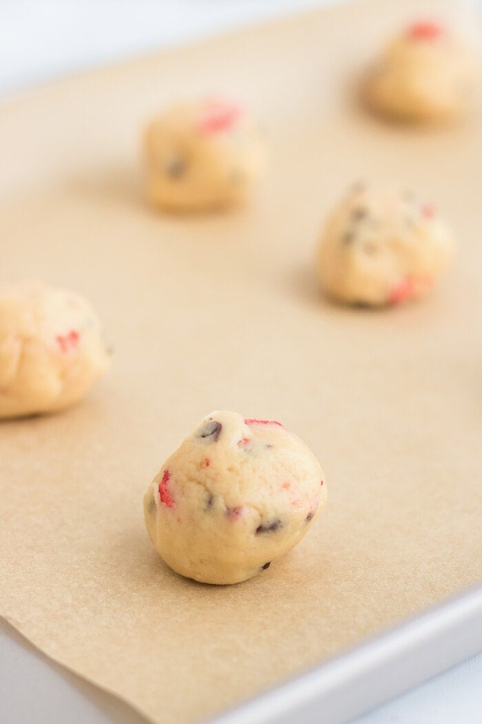 strawberry chocolate chip cookies dough balls on a baking sheet
