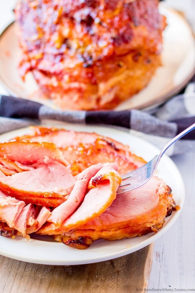 A fork lifting up a piece of the cooked ham.