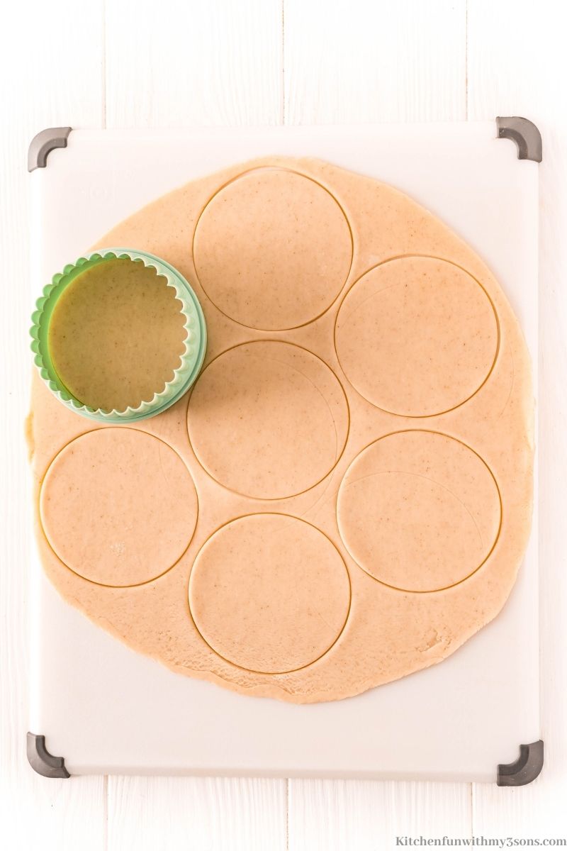 Using a biscuit cutter to cut circles out of the pie crust.