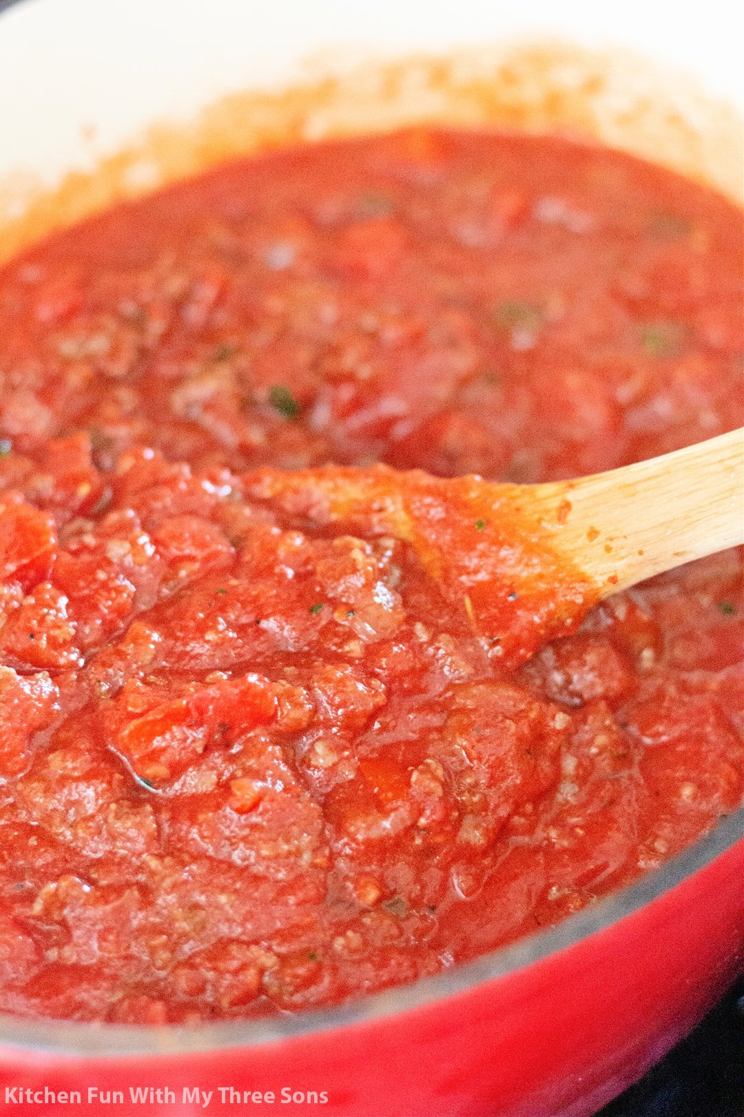 stirring the sauce in a Dutch oven with a wooden spoon.