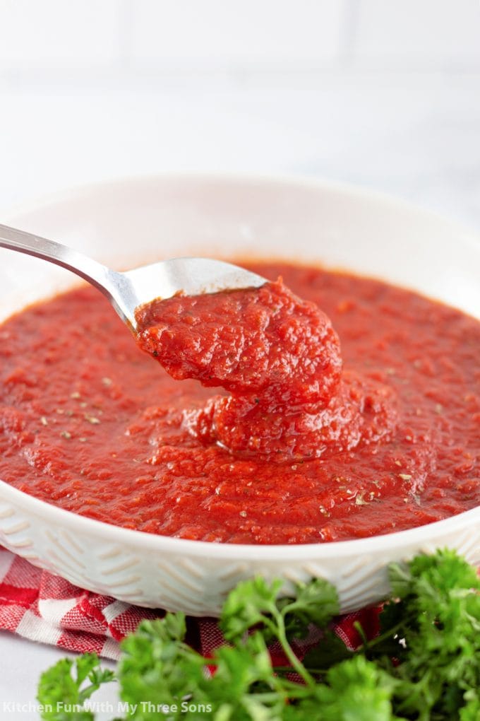 scooping pizza sauce with a spoon.