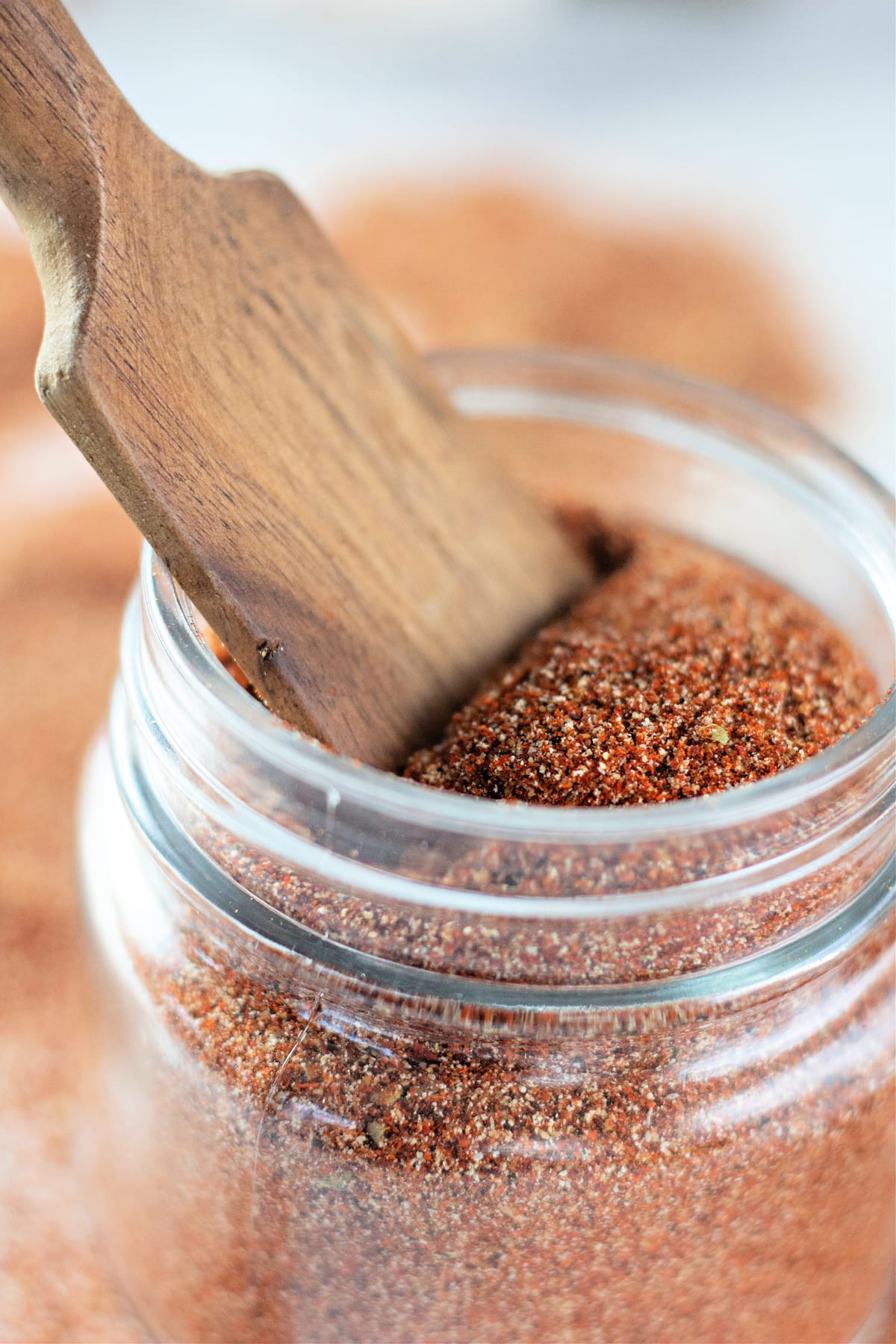 Close up of a wooden spoon in a jar of taco seasoning